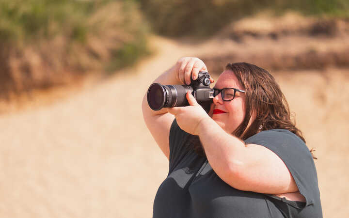 Katie in side profile, taking pictures using her DSLR camera. 